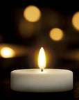 Single lit candle against a dark background with blurred lights