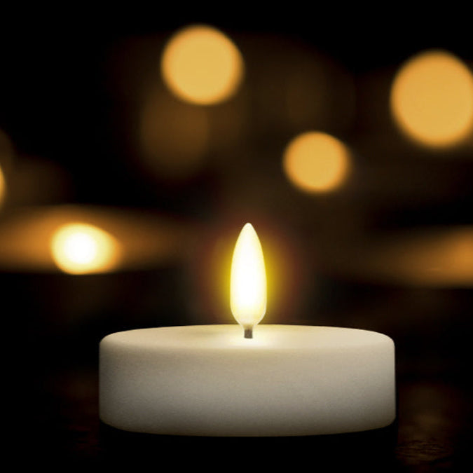 Single lit candle against a dark background with blurred lights